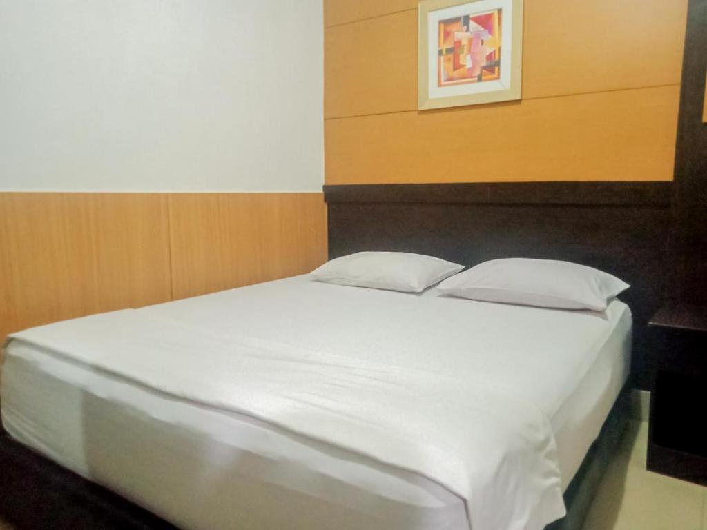 uma cama com lençóis e travesseiros brancos em um quarto em Homestay Akik Hijau Near Panakkukang em Pampang