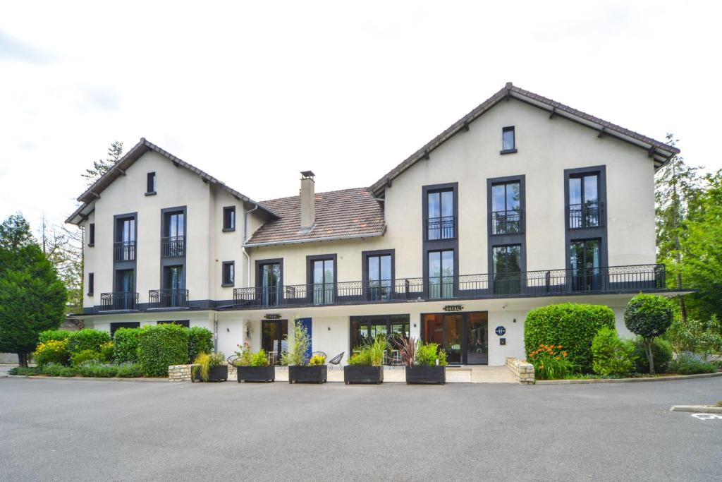 a large white house with black windows and plants at Logis - Hotel Restaurant La Mire in Vierzon