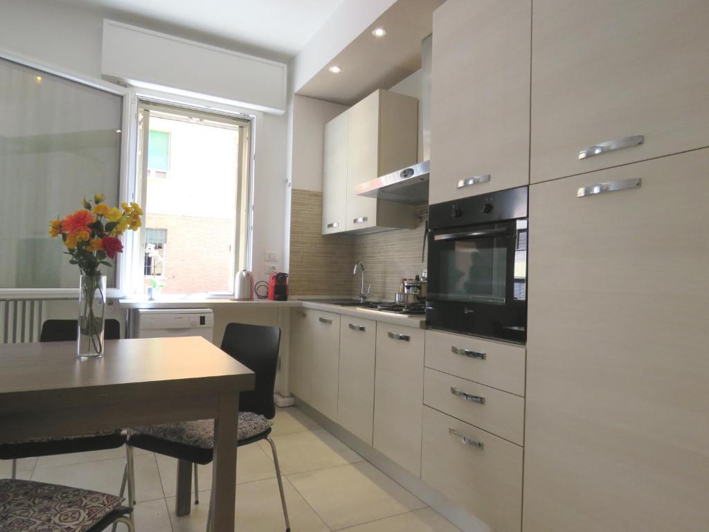 a kitchen with white cabinets and a table and a microwave at Pasubio Apartment in Bologna