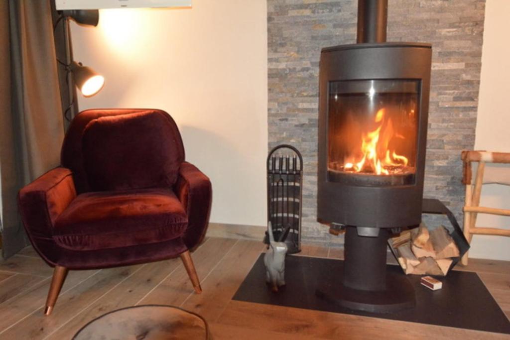 sala de estar con chimenea y silla en L'Aubépine 2 en Montalbert