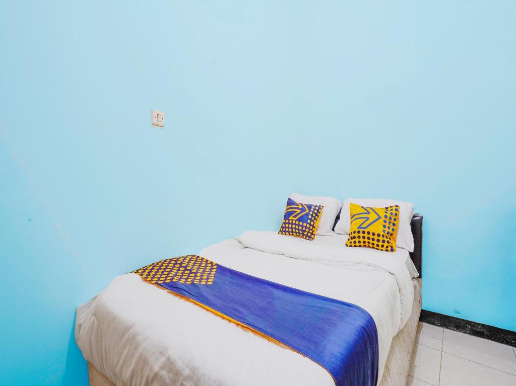 een blauwe kamer met een bed met kussens erop bij SPOT ON 91392 Pondok Basari in Bandung