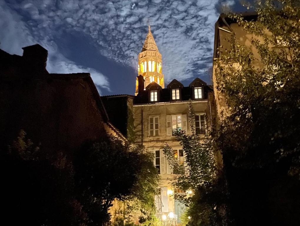 un bâtiment avec une tour d'horloge en haut dans l'établissement Le Jardin des Lys, à Saint-Léonard-de-Noblat