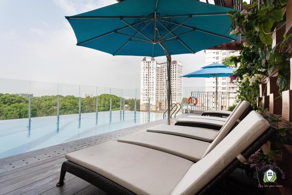 a row of benches with an umbrella on a balcony at Căn hộ Orchard Garden - SG Airport Homestay in Ho Chi Minh City