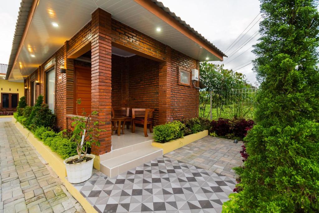 een stenen huis met een patio met een tafel bij RedDoorz @ Aldos Villa Silangit in Siborongborong