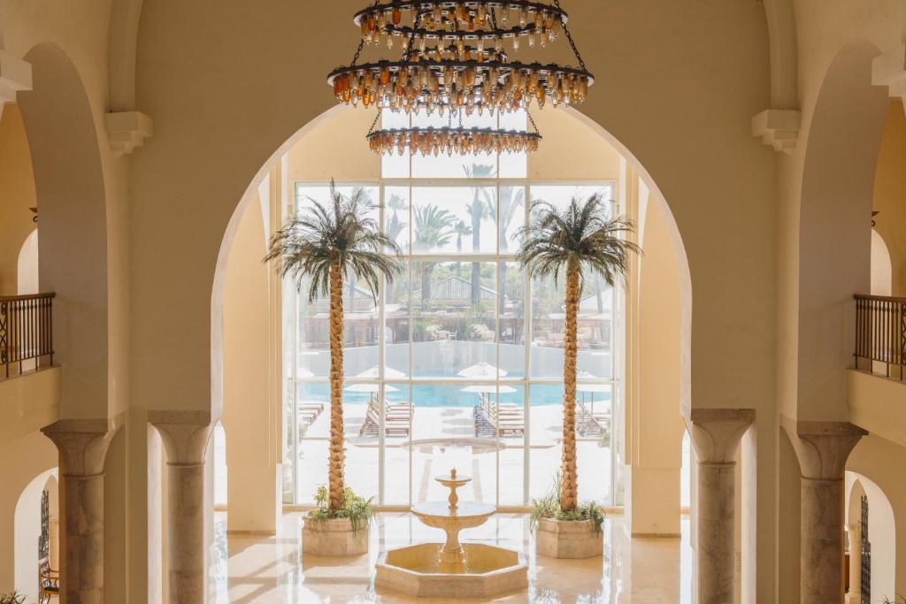 a chandelier hangs over a hallway with palm trees at The Residence Tunis in Gammarth