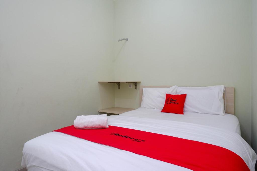 - un lit avec une couverture rouge et blanche dans l'établissement RedDoorz Syariah near Gerbang Tol Krapyak 2 Semarang, à Kalibanteng-kidul