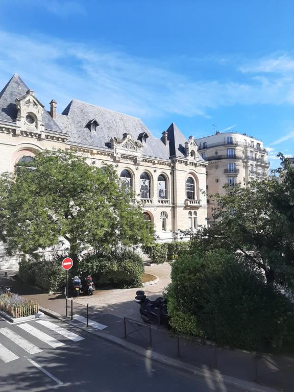 un grand bâtiment blanc avec un toit dans une rue dans l'établissement la studette du théâtre, à Boulogne-Billancourt