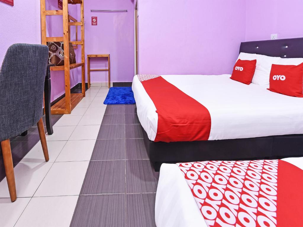 a hotel room with two beds and a chair at OYO 90561 Awan Biru Motel in Pantai Cenang