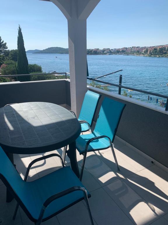 d'une table et de chaises sur un balcon avec vue sur l'eau. dans l'établissement Apartman Magica, à Grebaštica