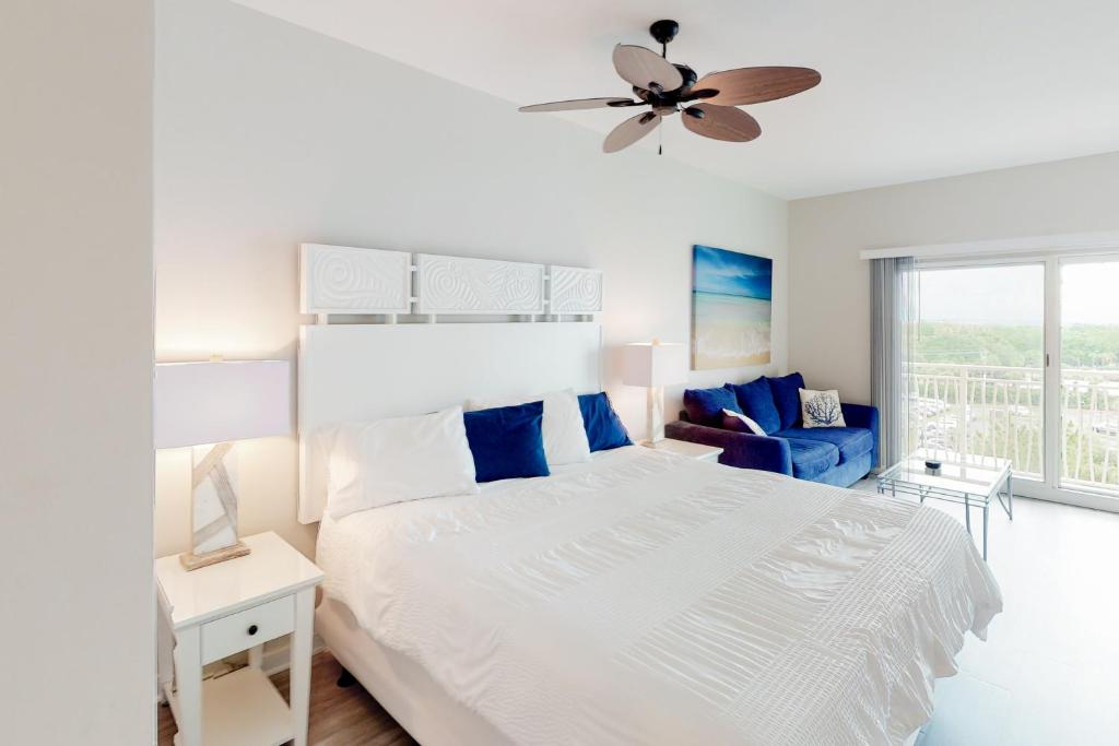 a white bedroom with a bed and a ceiling fan at Sandestin Luau 6525 in Destin