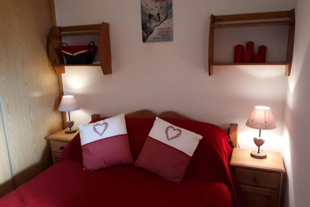 a bedroom with a red bed with two red pillows at Le Chalet de Montalbert 25C in Montalbert