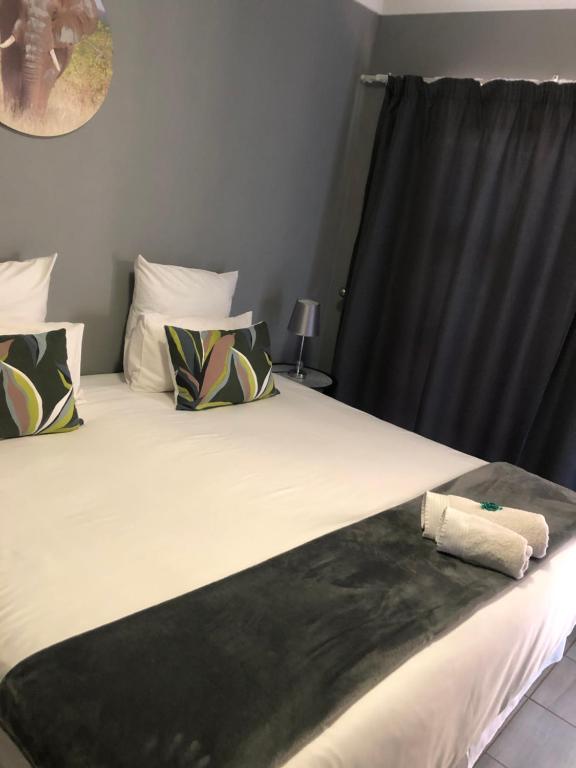 a bedroom with a large bed with a black curtain at Kudu Cottages in Kathu
