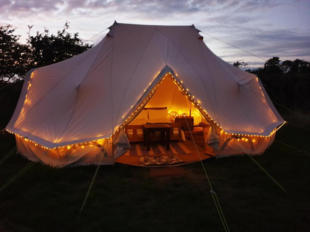 a large white tent with lights in a field at 6m Emperor tent near Whitby with log burner in Liverton