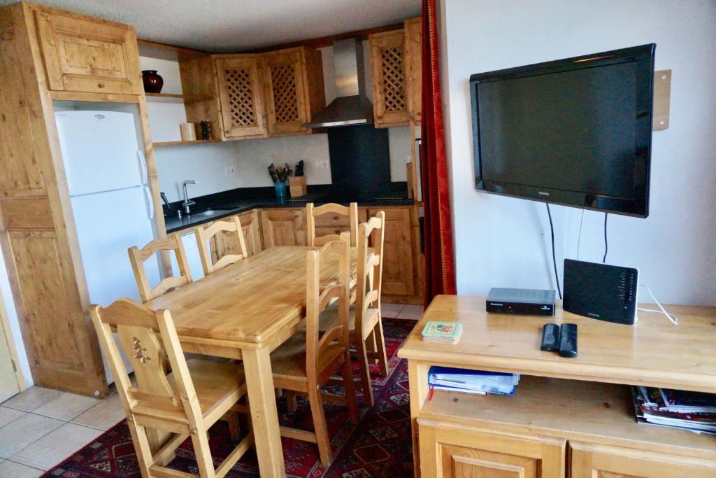 cocina con mesa de madera y TV en la pared en Chalet de Montalbert 32C 5-7 pers en Aime La Plagne