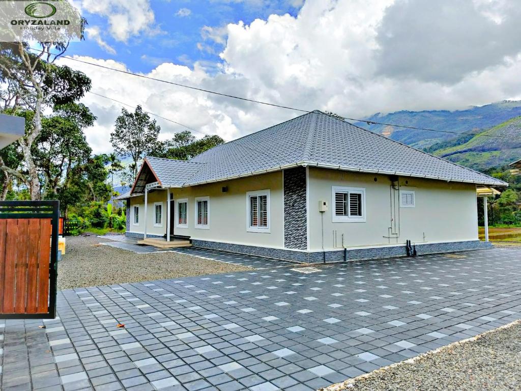 a small white house with a driveway at Oryzaland Holiday Villa in Munnar