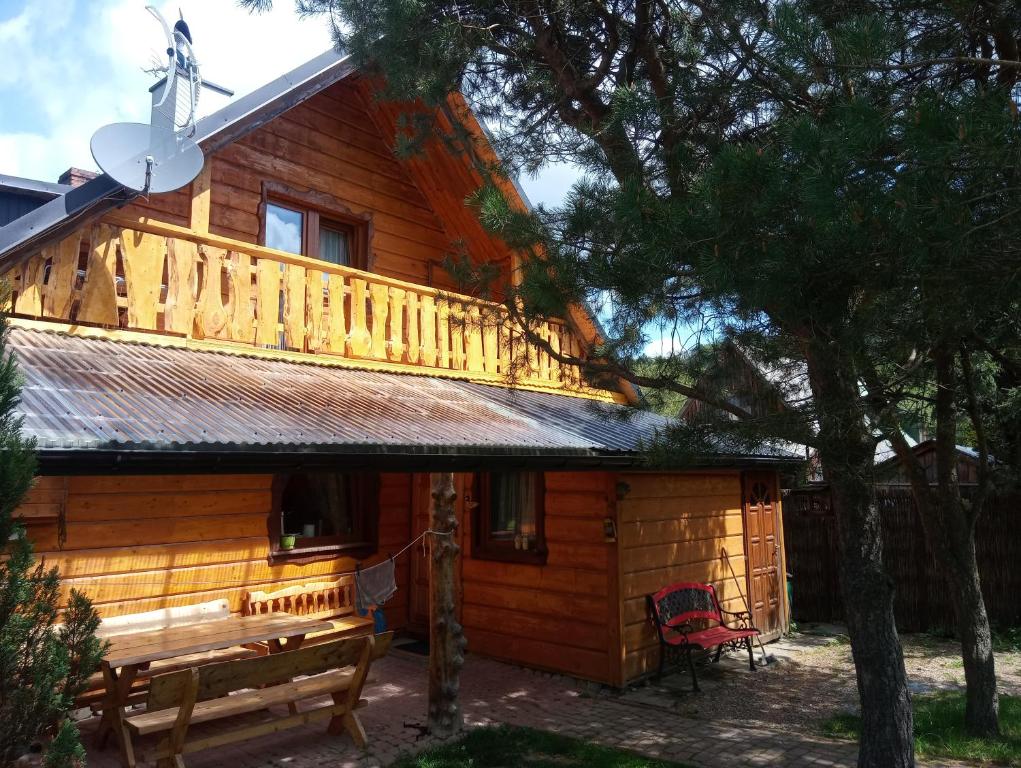a wooden cabin with a balcony on top of it at Cztery Pory Roku - Dom in Lutowiska