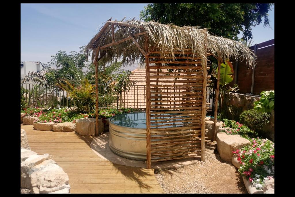 a garden with a large barrel and a straw hut at RAKEFET - Traveler's House - EILAT in Eilat