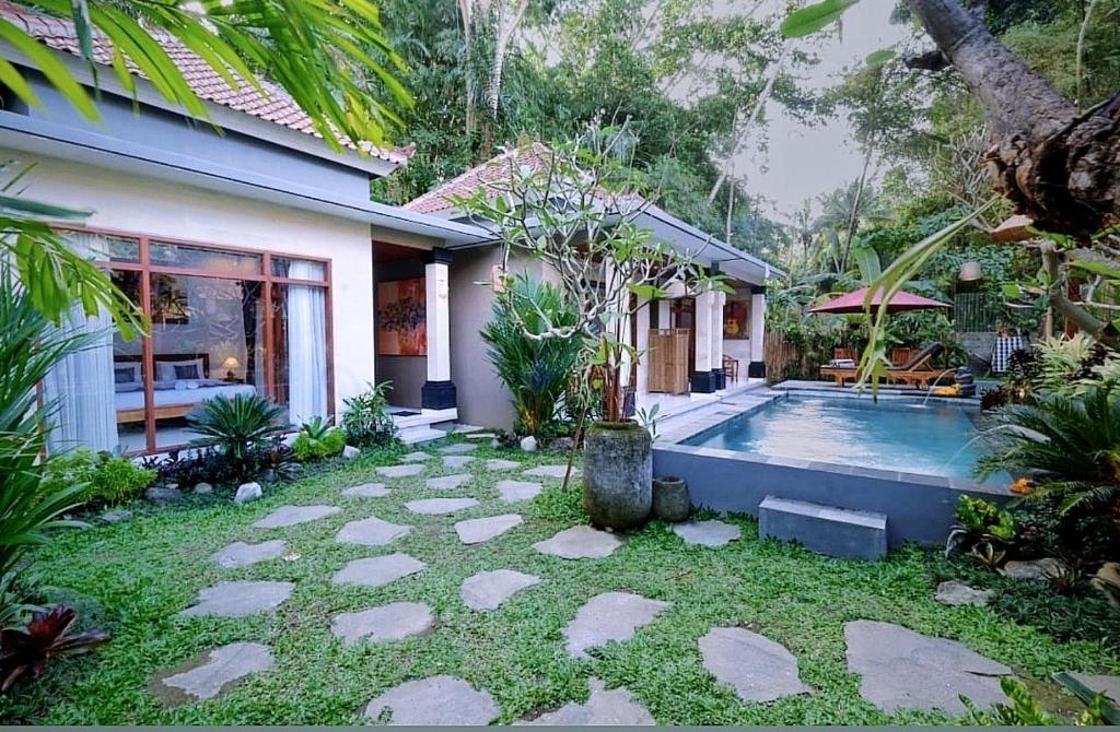 um quintal com uma piscina e uma casa em D'bunut villa ubud em Ubud