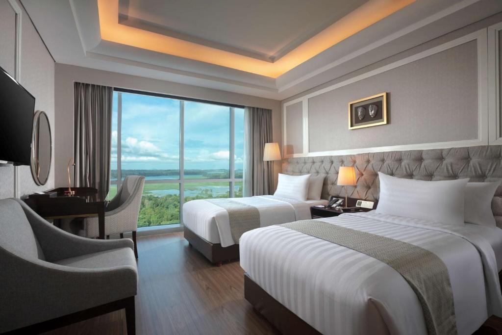 a hotel room with two beds and a desk and a window at Best Western Premier Panbil in Batam Center