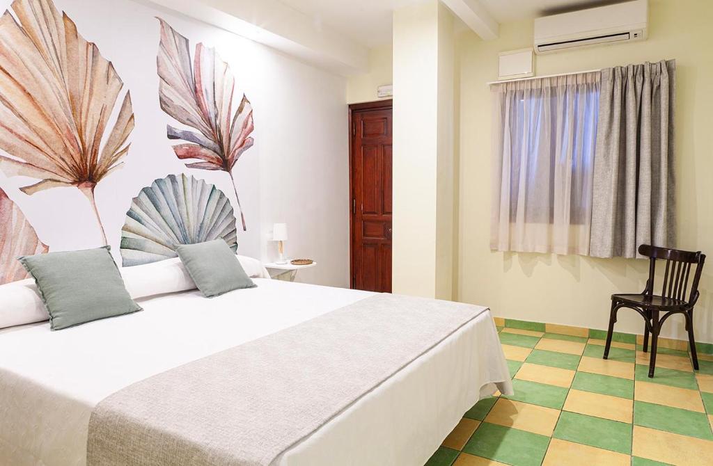 a bedroom with a large white bed and a chair at Hostal León Dormido in Polop