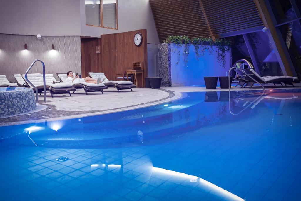 阿尼克什奇艾的住宿－阿尼克什奇艾-維爾紐斯SPA酒店，酒店的游泳池设有椅子和时钟,可供2人使用
