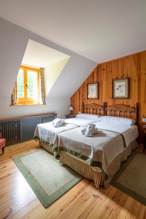 1 dormitorio con 2 camas y paredes de madera en Parador de Bielsa, en Espierba