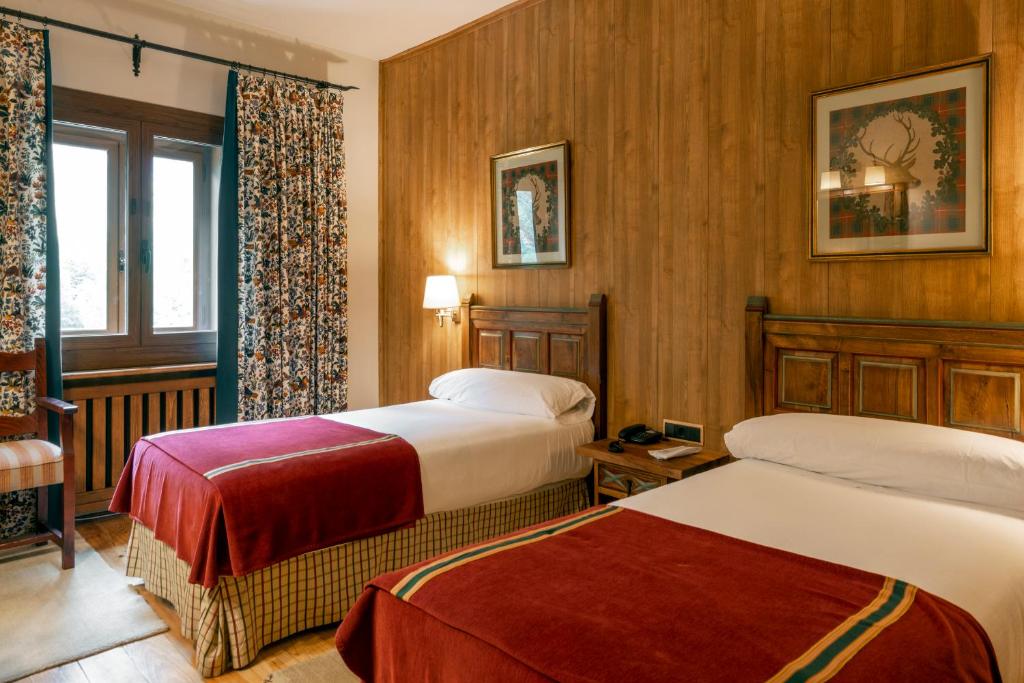 Una habitación de hotel con dos camas y una ventana. en Parador de Bielsa, en Espierba