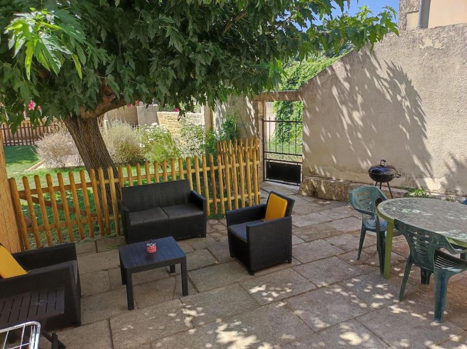 um pátio com cadeiras e mesas e uma cerca em Mas provençal au cœur des vergers em Vallabrègues