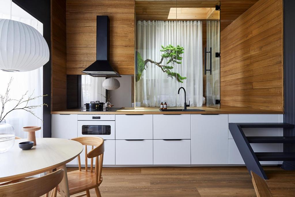 uma cozinha com armários brancos e uma mesa em The Ryokan - Zen em Sydney
