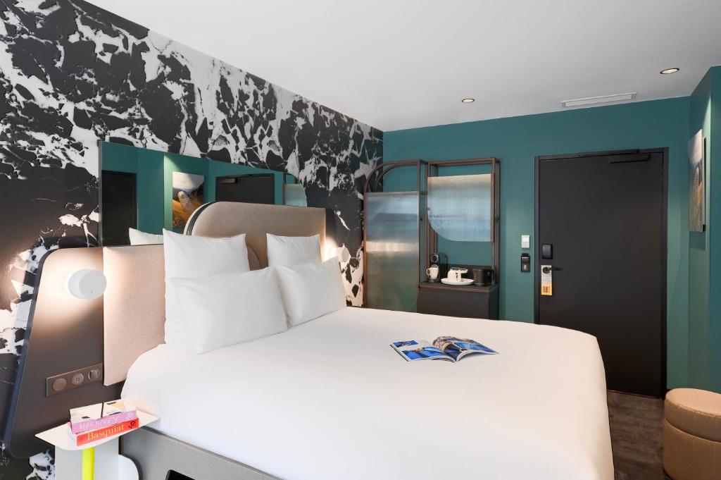 een slaapkamer met een wit bed en een blauwe muur bij Tribe Paris La Defense Esplanade in Courbevoie