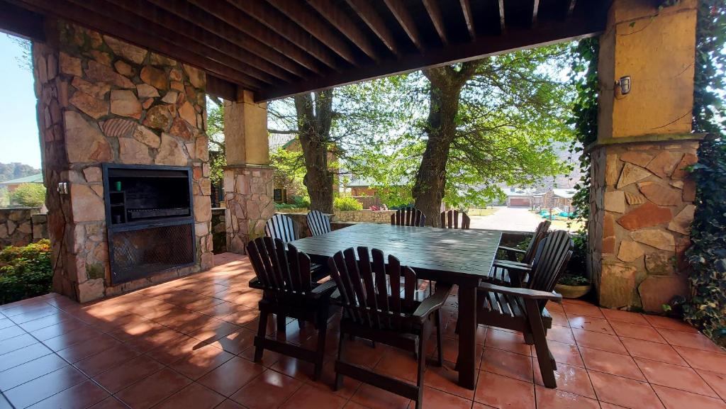 a wooden table and chairs on a patio with a fireplace at Catmandu in Dullstroom