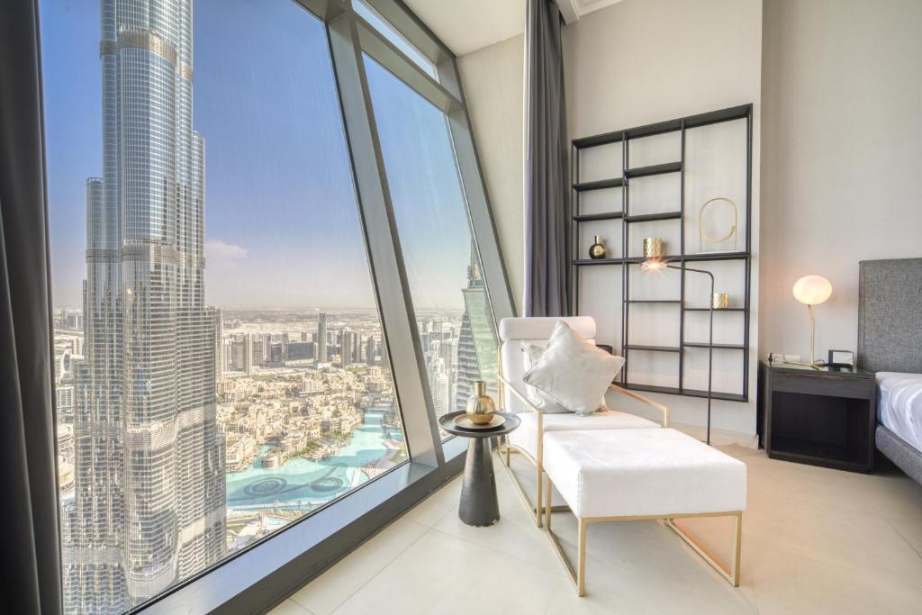 ein Schlafzimmer mit einem weißen Stuhl und großen Fenstern in der Unterkunft Burj Vista, Downtown Dubai - Burj Khalifa View - Mint Stay in Dubai