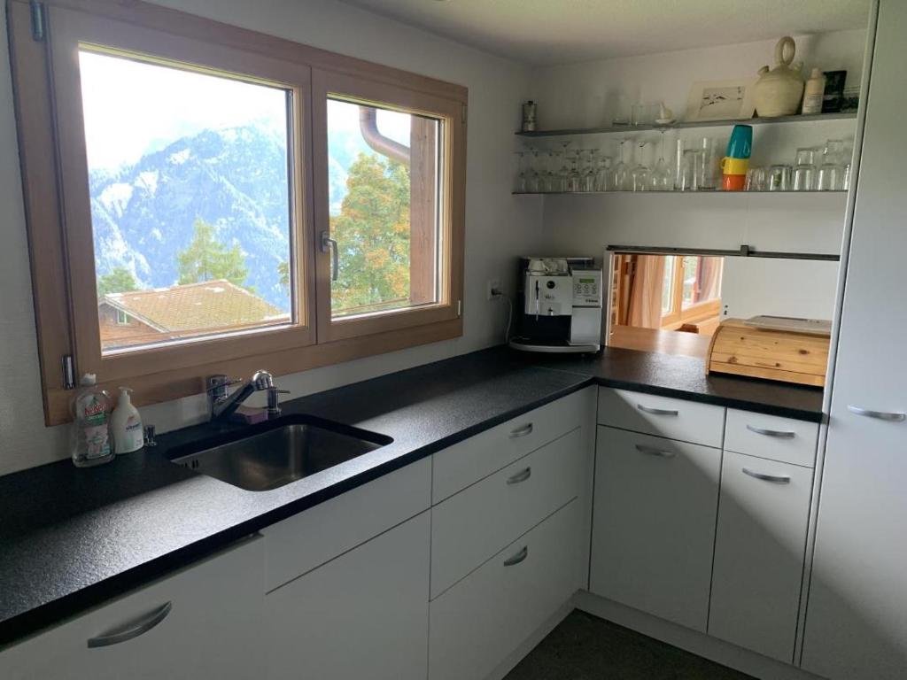 a kitchen with white cabinets and a sink and a window at Revier Silberdistel im Schwettiberg in Braunwald