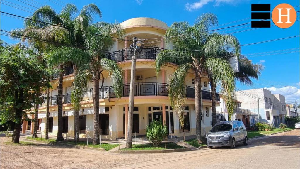 a car parked in front of a building with palm trees at El Hotelito in San José