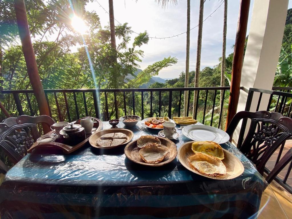 a table with plates of food on a balcony at adam's apple homestay in Ella