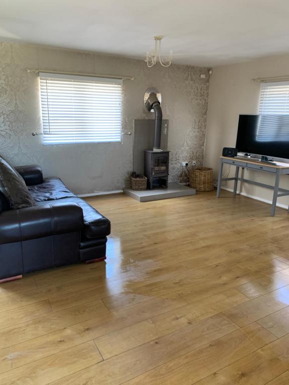 sala de estar con sofá negro y suelo de madera en Arkenfield farm cabin, en East Bridgford