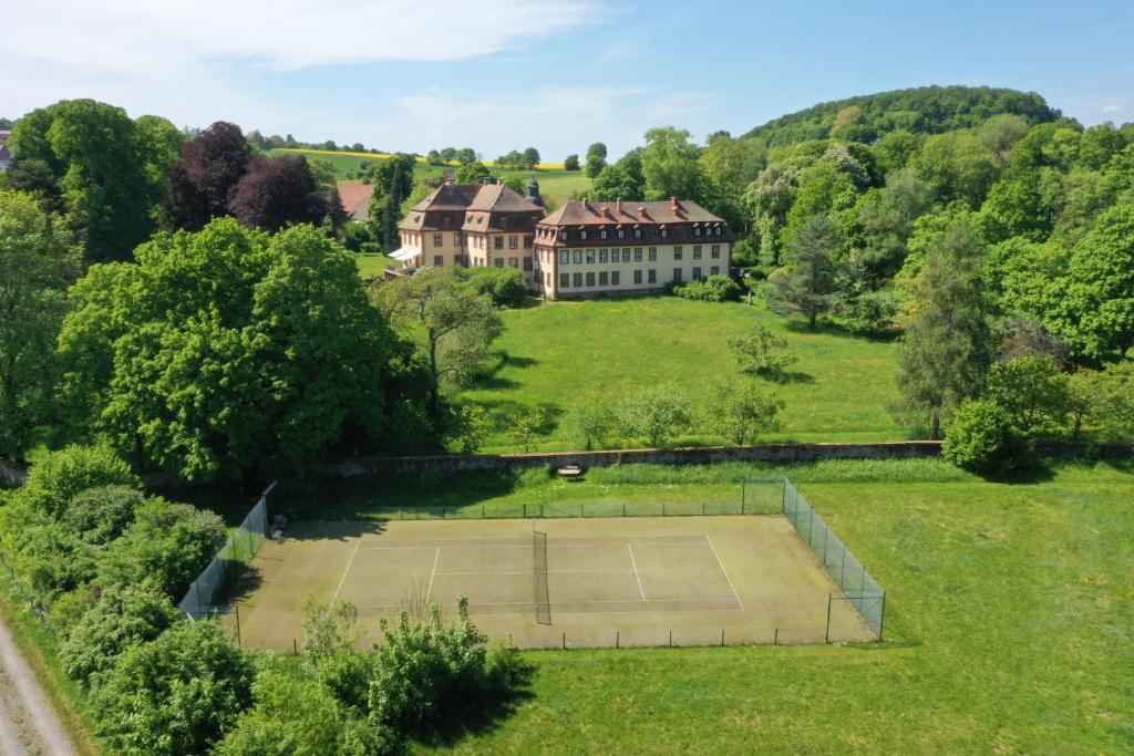 eine Luftansicht eines großen Hauses mit Tennisplatz in der Unterkunft Private apartment in historic castle from 1608 with tenniscourt in Zeitlofs