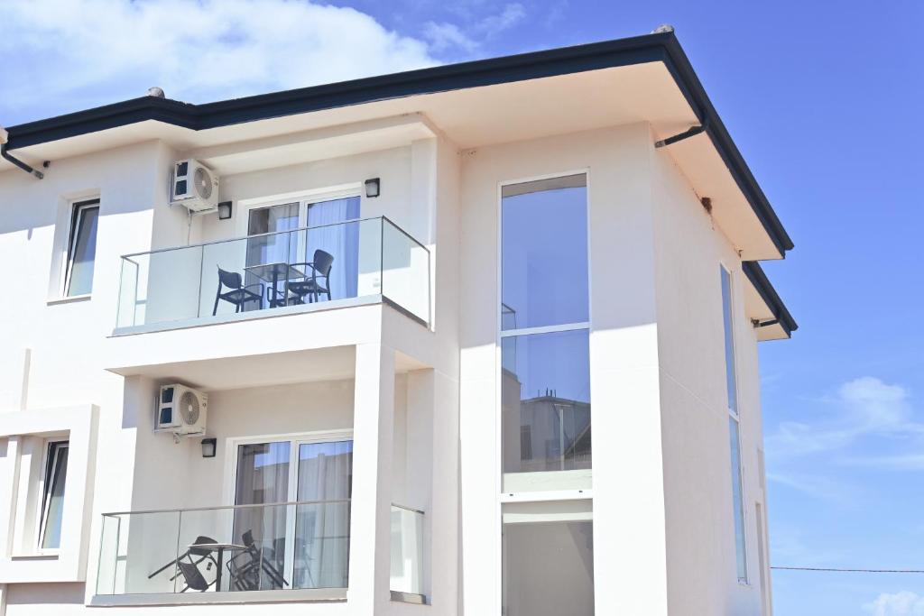 a white house with a glass balcony at SEA & LAKE VIEW VILLA in (( Kalive Gjoka ))