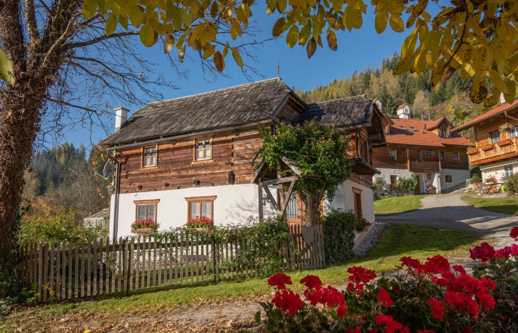 une maison en bois avec une clôture et des fleurs dans l'établissement Troadkasten - Ferienhaus am BIO-Bergbauernhof, à Aflenz Kurort