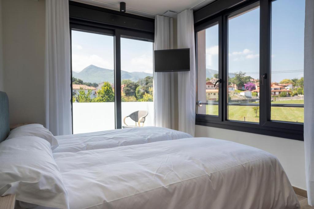 a bedroom with a white bed and a large window at Hotel A Mares in Celorio
