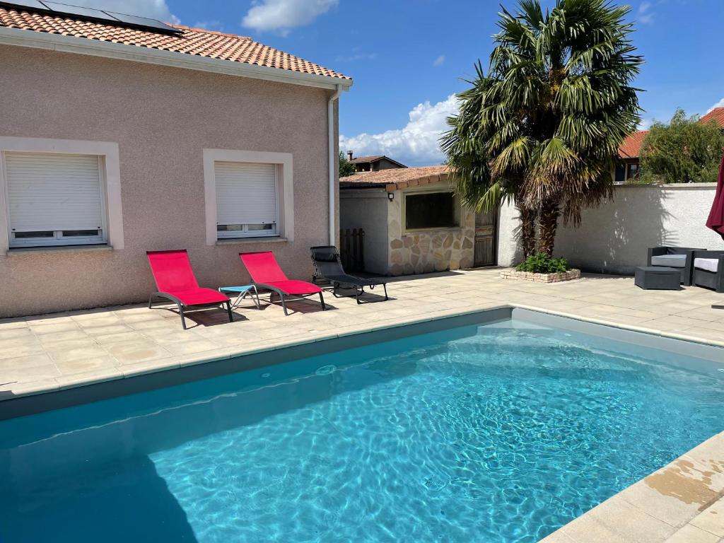 uma piscina com duas cadeiras vermelhas ao lado de uma casa em Maison entière 4 lits 8 pl avec jacuzzi proche du safari de Peaugres em Anneyron