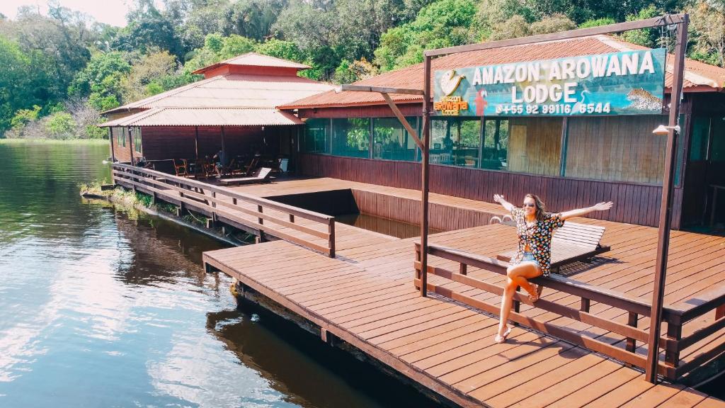 a woman jumping off a dock into the water at Amazon Arowana Lodge in Careiro