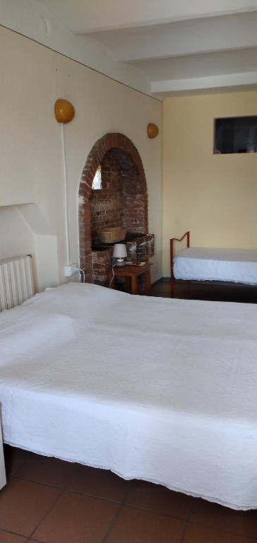 uma grande cama branca num quarto com lareira em B&B La Verna em Casola