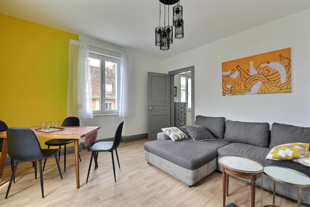 uma sala de estar com um sofá, uma mesa e cadeiras em "Urbaine Cosy" Elégance, confort et détente en Alsace "Les Péri-Urbaines" em Riedisheim