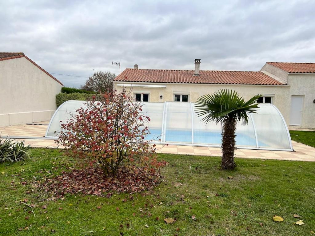 uma casa com uma palmeira e uma piscina em Villa de 3 chambres avec piscine privee jardin clos et wifi a Saint Froult a 1 km de la plageB em Saint-Froult