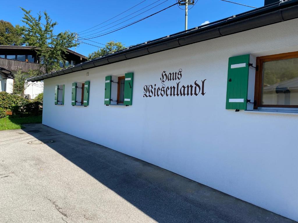 a white building with green windows and a sign on it at Ferienhaus Wiesenlandl in Bischofswiesen