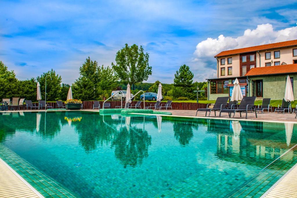 una piscina en un complejo con sillas y un edificio en Hotel Forest Hills, en Zirc