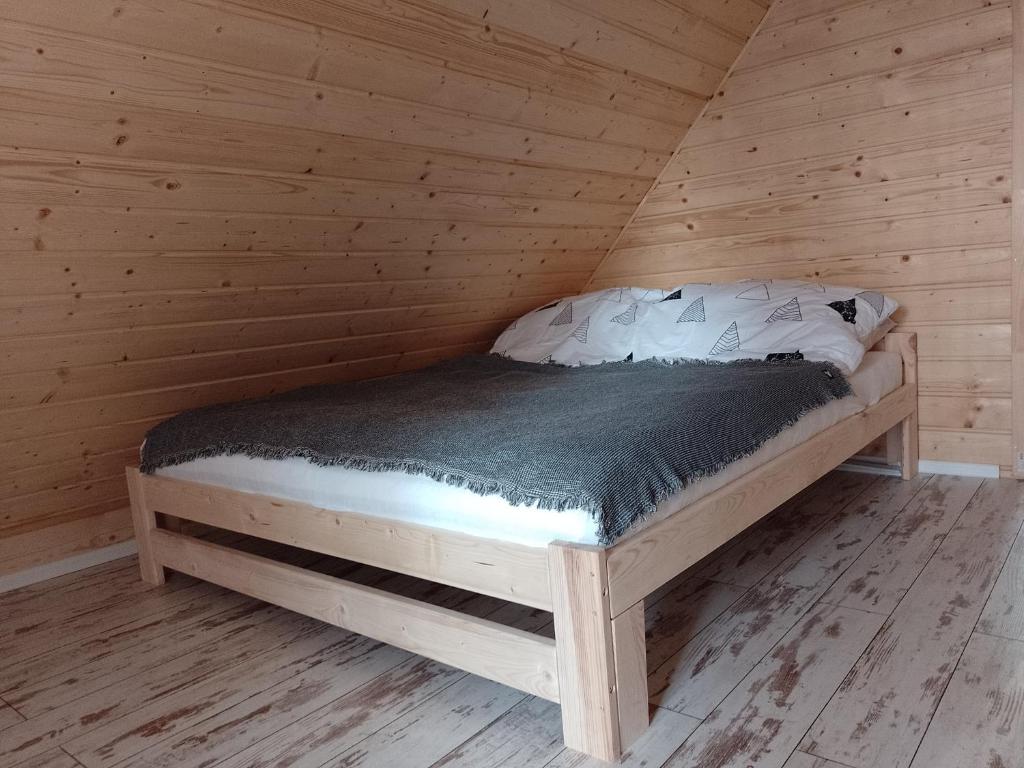 Bett in einem Holzzimmer in einer Hütte in der Unterkunft Domki letniskowe Balia sauna Leśny Czar in Raków