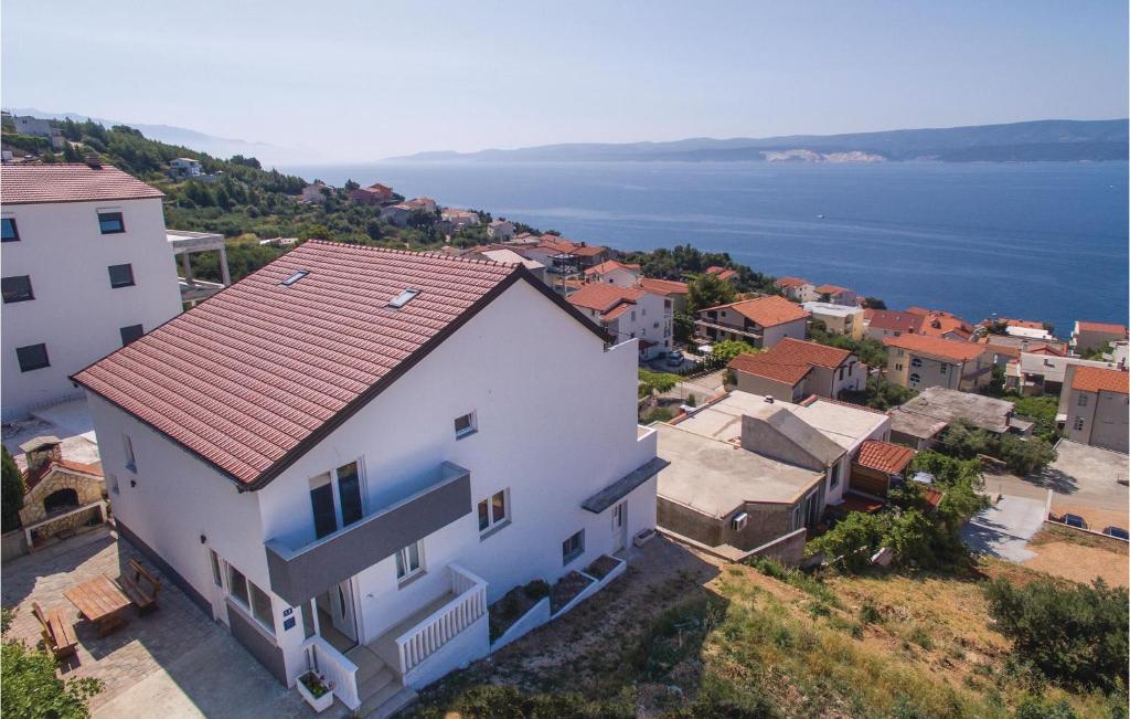 a white house with a red roof next to the water at Amazing Apartment In Stanici With 3 Bedrooms And Wifi in Čelina