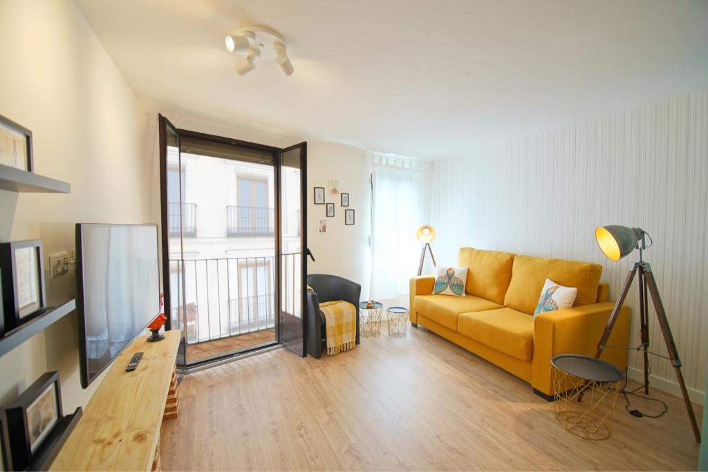 a living room with a yellow couch and a window at Piso Turqueta, Céntrico Casco Antiguo Castro Urdiales in Castro-Urdiales